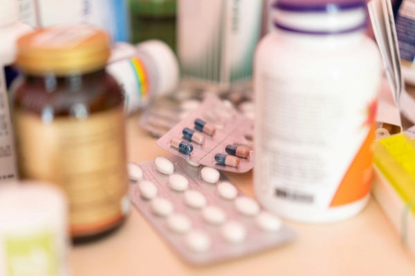 Frascos e blister de cápsulas e comprimidos de multivitamínicos e melatonina sobre mesa