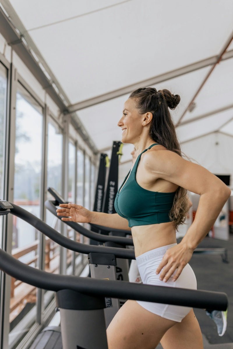 Mulher praticando exercício em esteira na academia, estilo de vida fitness
