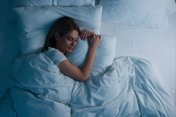 Mulher dormindo tranquilamente na cama, ambiente escuro, representando sono de qualidade.