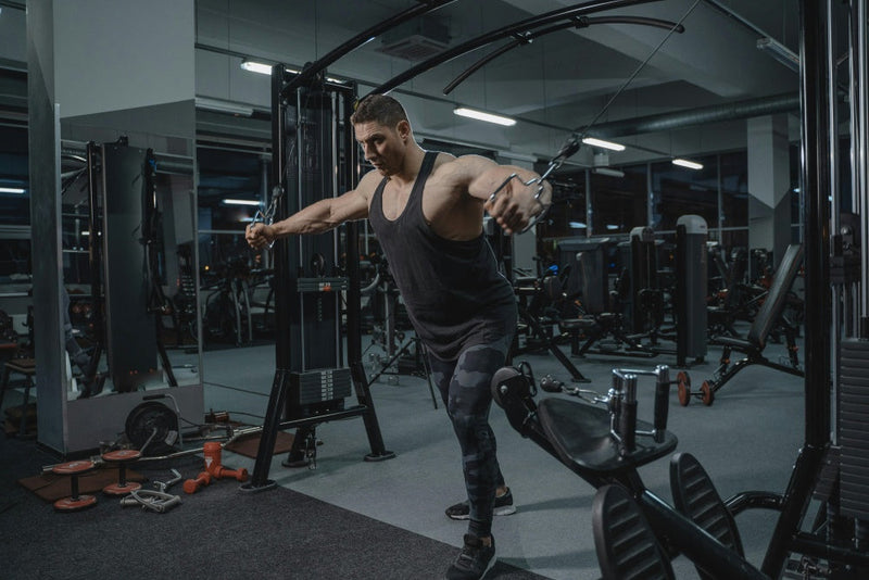 Homem malhando no aparelho de cross over em academia moderna, treino de musculação e desempenho