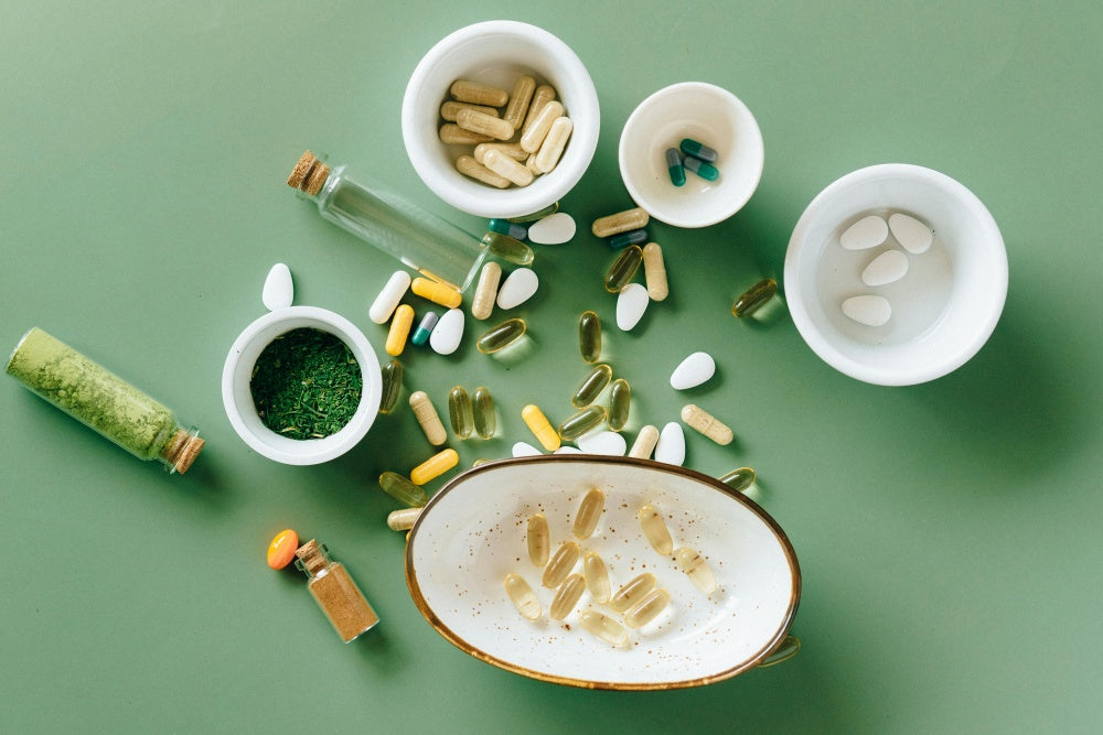 Cápsulas, comprimidos e suplementos diversos em potes sob fundo verde, variedade de suplementos alimentares.
